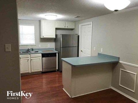 A kitchen with a refrigerator, sink, and cabinets.