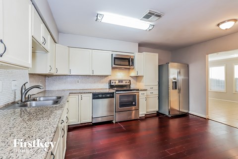 A kitchen with white cabinets and a stainless steel refrigerator.