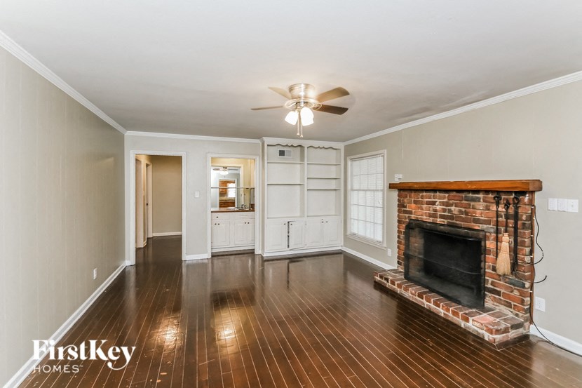 a living room with a brick fireplace and wooden floors