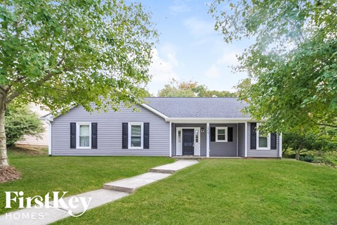 a gray house with a lawn and trees