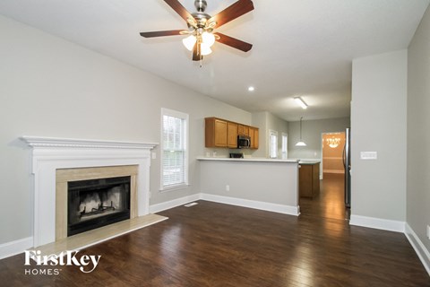 A spacious living room with a fireplace and a ceiling fan.
