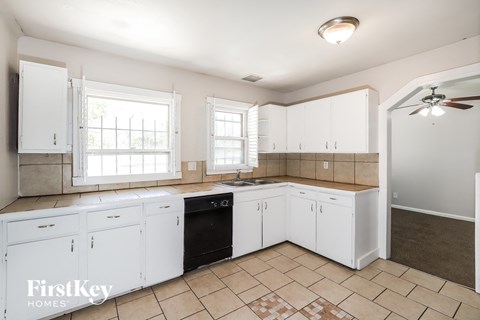 A kitchen with white cabinets and a black dishwasher.