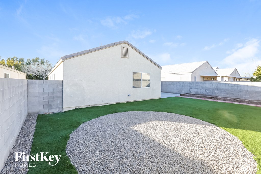 a backyard with a white house and a green lawn