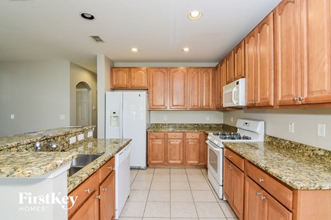 A kitchen with brown cabinets and a granite counter top.