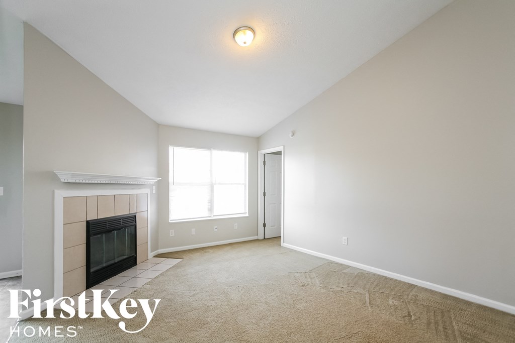 an empty living room with a fireplace and a window