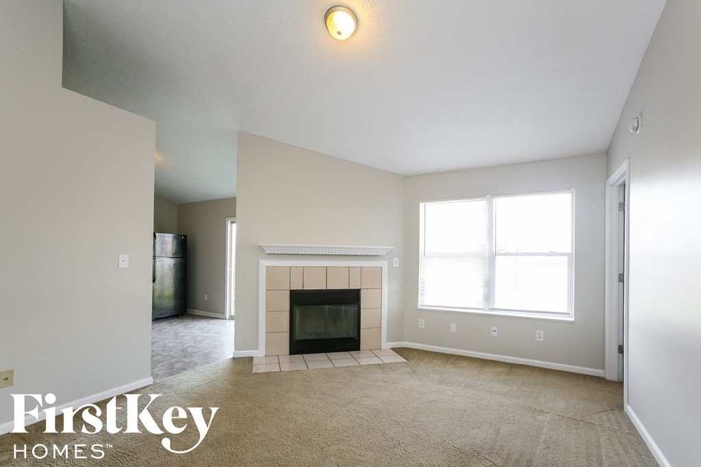 an empty living room with a fireplace and a window