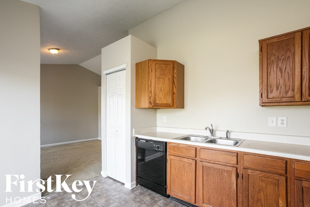a kitchen with wooden cabinets and a black dishwasher and sink