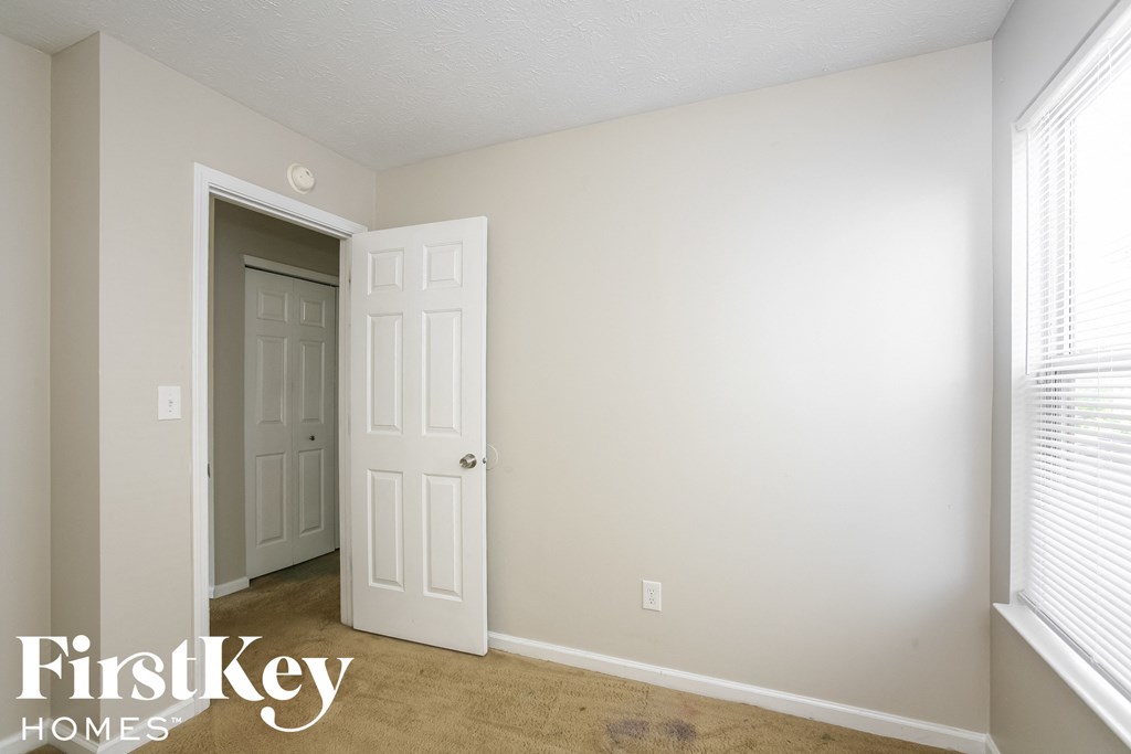 a bedroom with a white door and a closet and a window