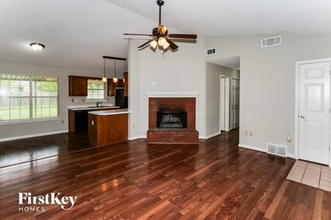 A spacious living room with wood flooring and a fireplace.
