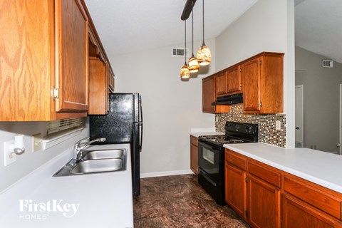 A kitchen with wooden cabinets and a black fridge.