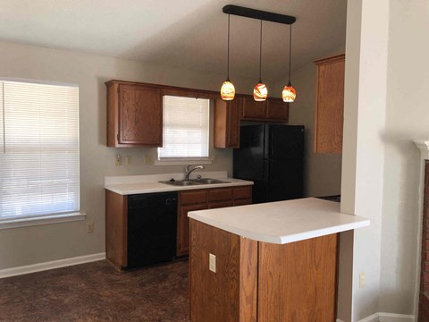 A kitchen with wooden cabinets and a black refrigerator.
