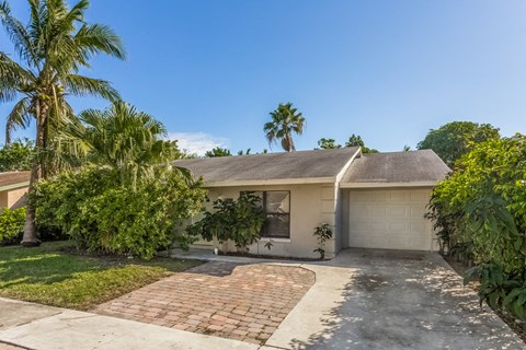 a white house with palm trees and a driveway