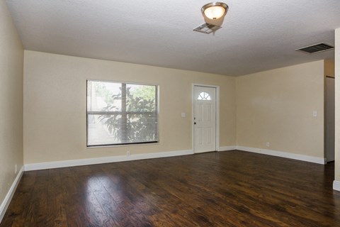 an empty living room with wood floors and a window