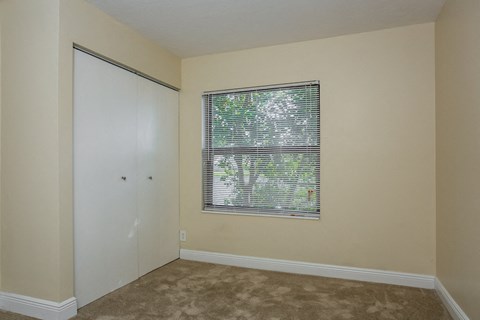 an empty bedroom with a window and a closet