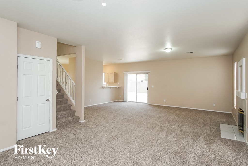 an empty living room with a staircase and a white door