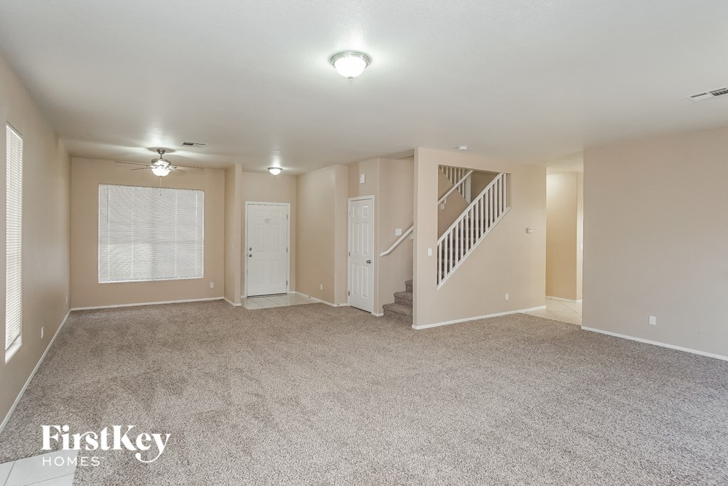 the living room of an empty house with carpet and a staircase