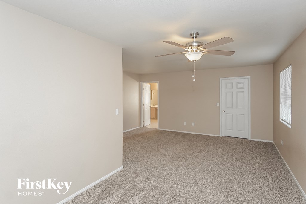 the spacious living room with ceiling fan and carpeting