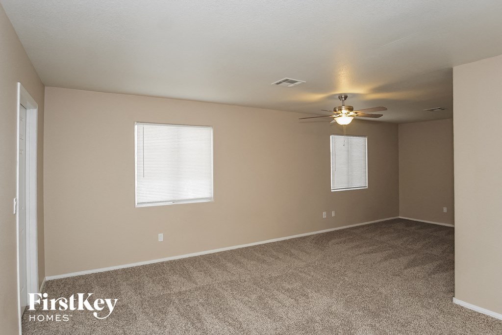 an empty living room with carpet and a ceiling fan
