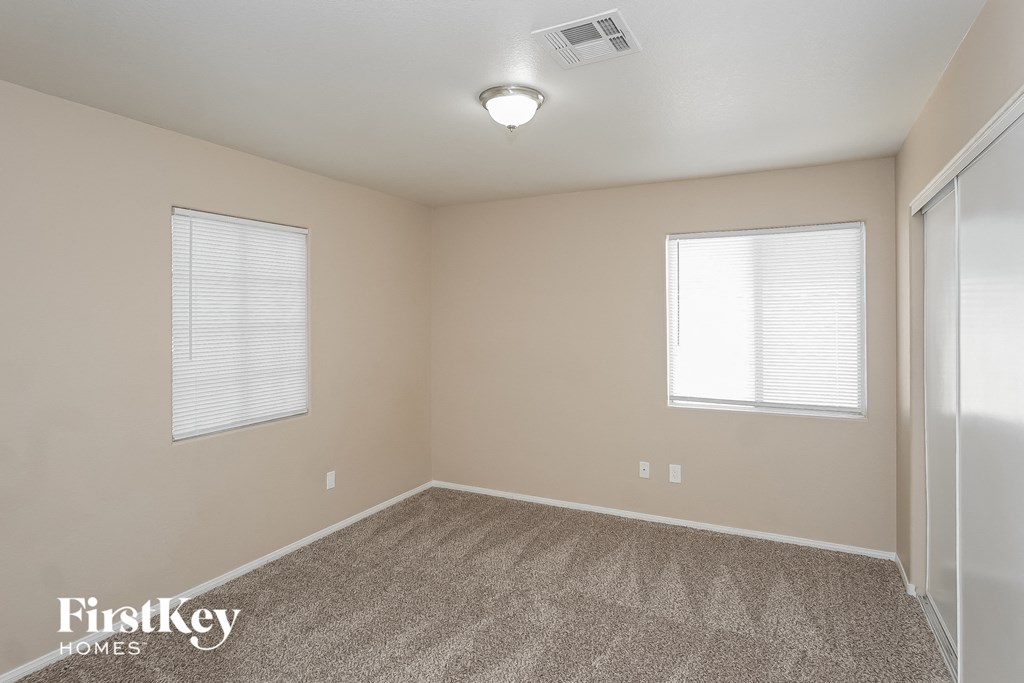 the spacious living room with carpeted flooring and two windows