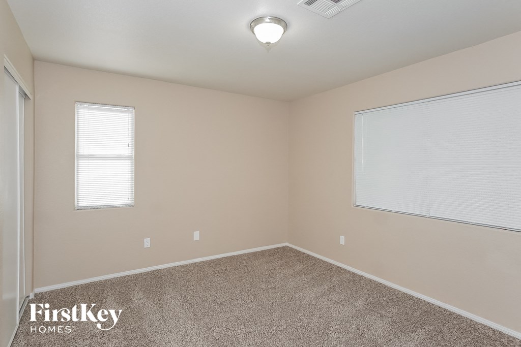 the spacious bedroom with carpeted flooring and two windows