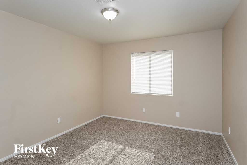 the spacious bedroom with carpeted flooring and a window