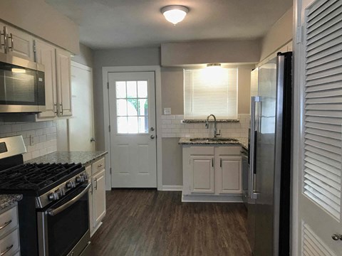 a kitchen with a stove and a sink and a door