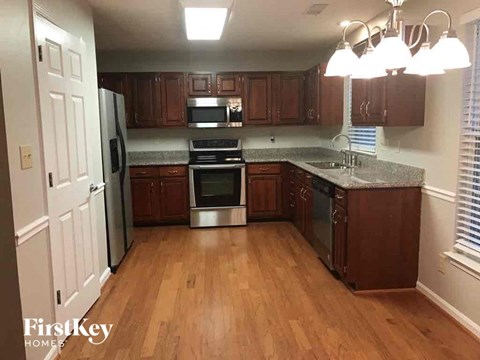 an empty kitchen with wooden floors and stainless steel appliances