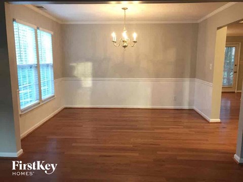 an empty dining room with wood floors and a chandelier