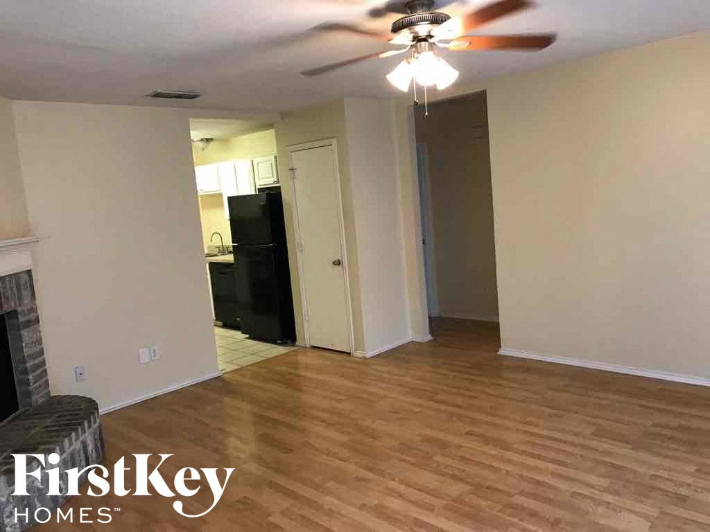 an empty living room with wood floors and a ceiling fan