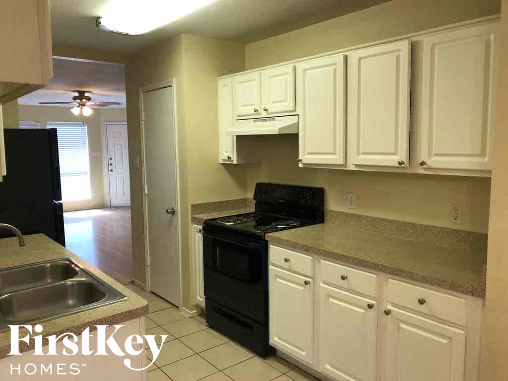 a kitchen with white cabinets and a black stove and a sink