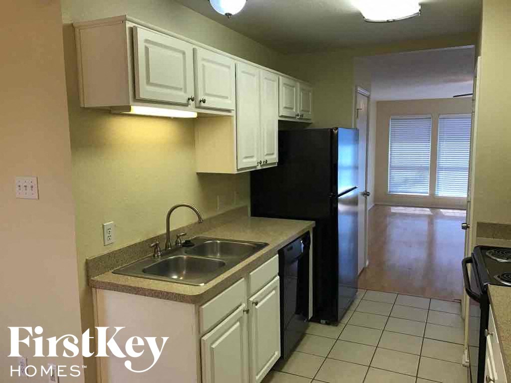 a kitchen with white cabinets and a sink and a black refrigerator
