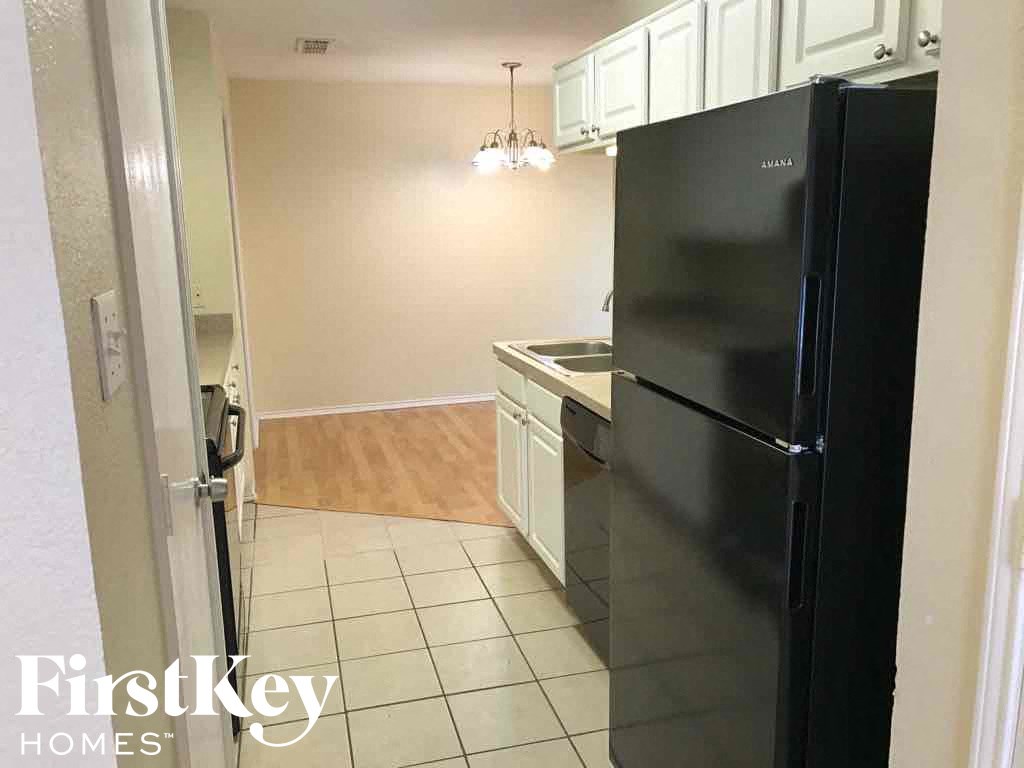 a kitchen with a black refrigerator and white cabinets