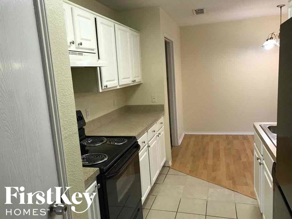 a small kitchen with white cabinets and a black stove