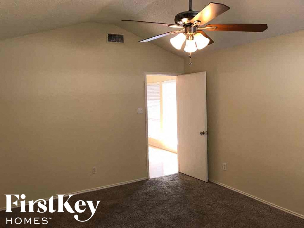an empty bedroom with a ceiling fan and a door to a closet