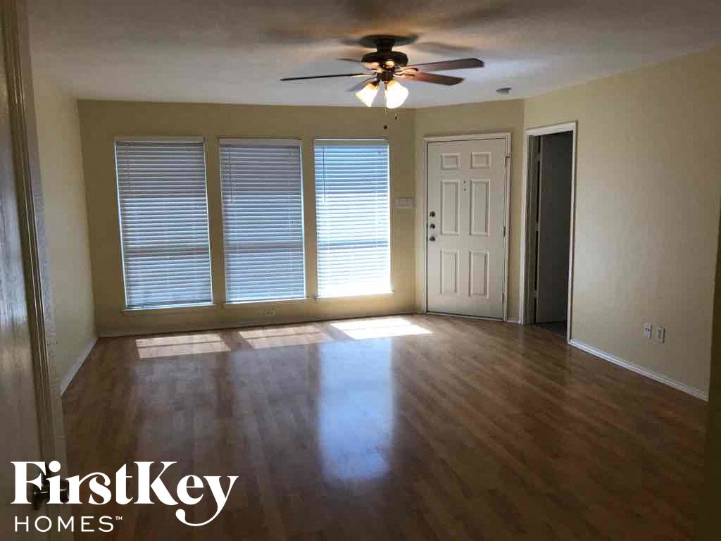 an empty living room with a ceiling fan and wood floors