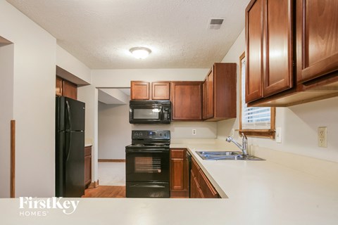 A kitchen with wooden cabinets and a black fridge.