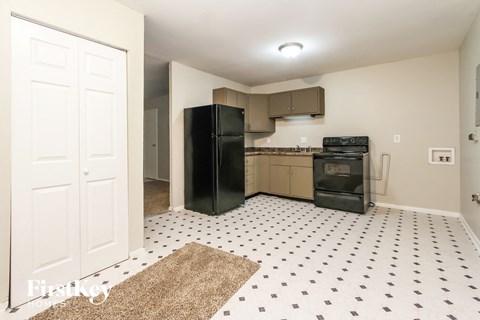 A kitchen with black appliances and a white and black checkered floor.