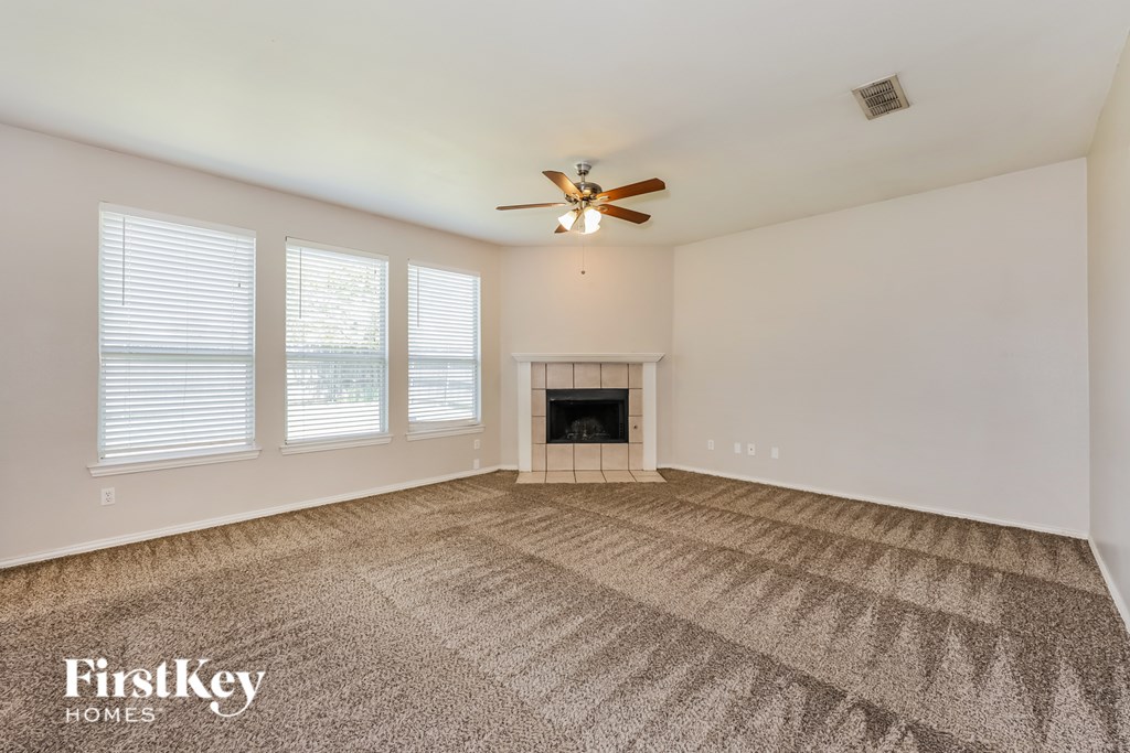 A spacious living room with a fireplace and a carpeted floor.