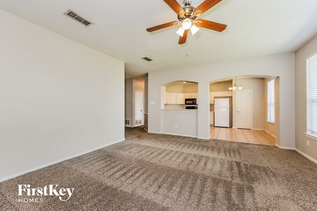 A spacious room with a ceiling fan and a carpeted floor.