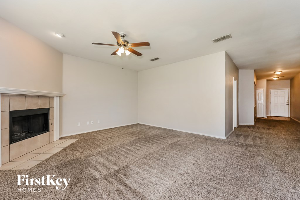 A spacious room with a fireplace and a carpeted floor.
