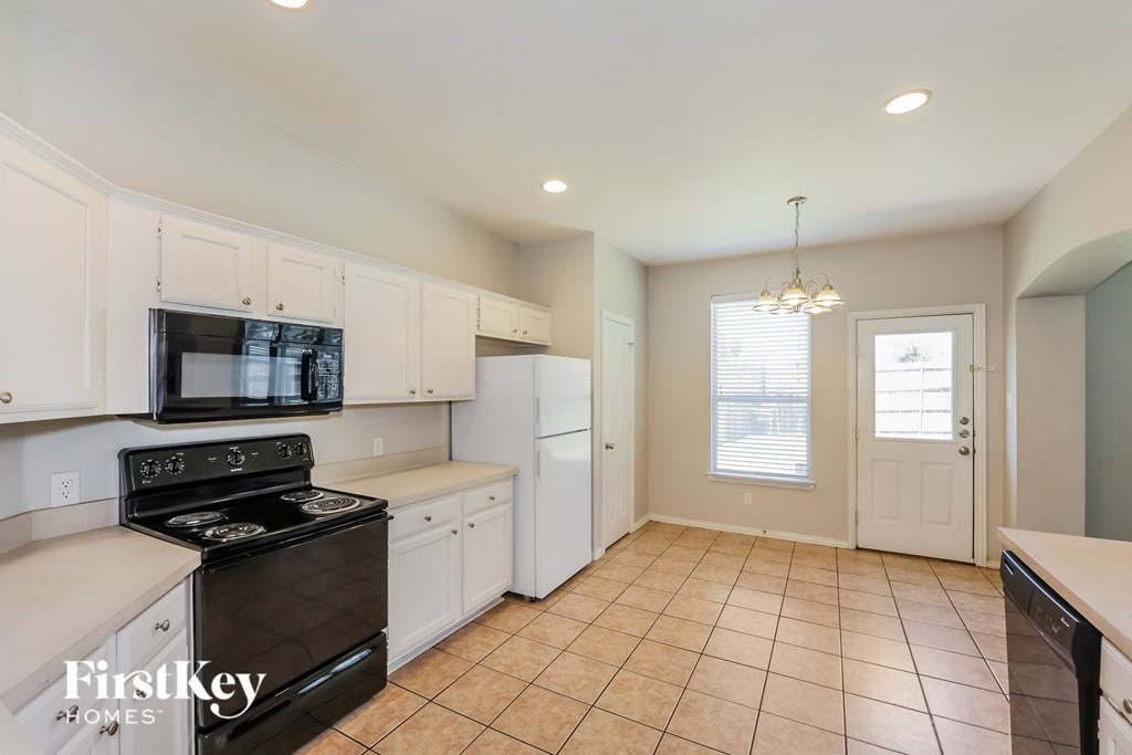 A kitchen with white cabinets and a black stove top oven.