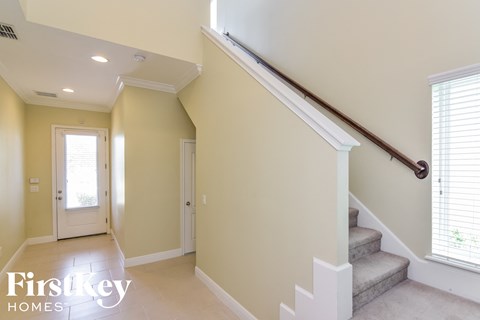 A staircase with a wooden handrail leads up to a window.
