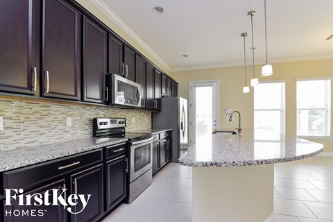 A kitchen with dark brown cabinets and a granite countertop.