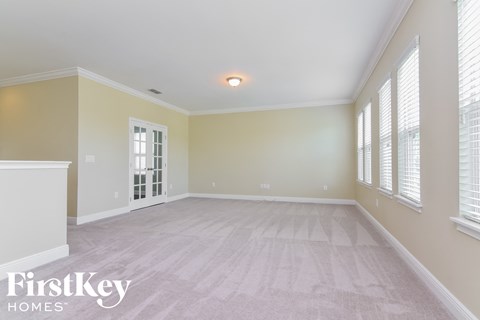 A spacious room with a carpeted floor and a window with blinds.