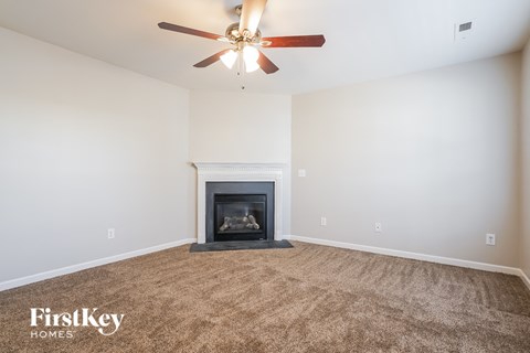 A living room with a fireplace and a ceiling fan.
