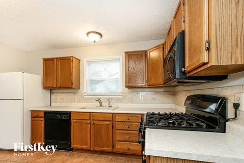A kitchen with wooden cabinets and a black stove top oven.