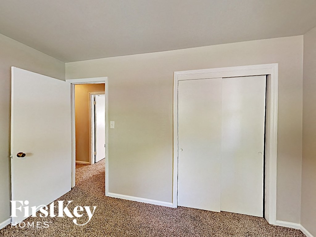 A carpeted room with a white door and a white wall.
