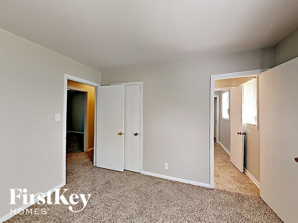 A carpeted room with a white door and a window.