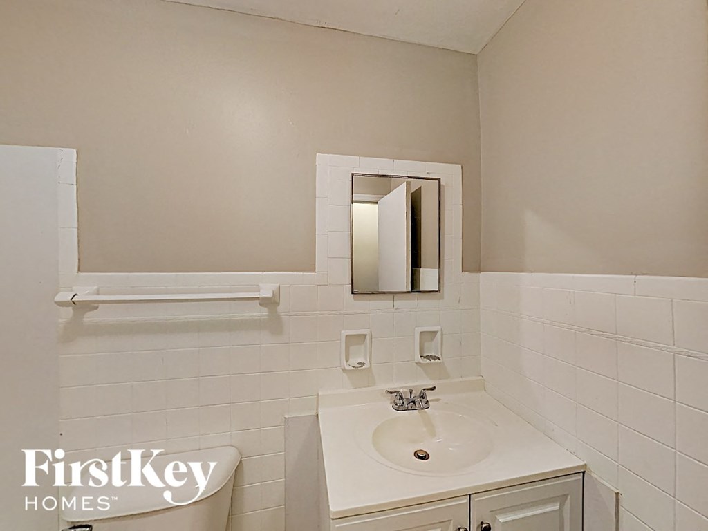 A white bathroom with a sink and mirror.
