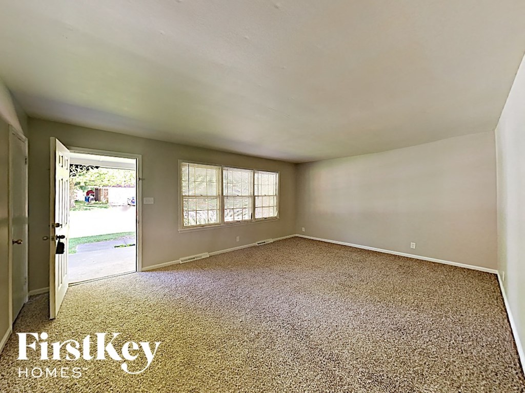 A room with a carpet floor and a door leading outside.